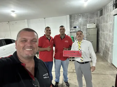 Dr. Thiago com a equipe do Escritório do Automóvel e a placa da loja