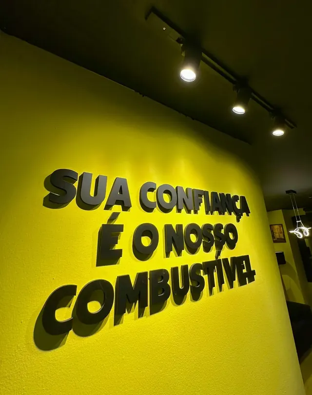 Parede amarela com a frase Sua confiança é o nosso combustível