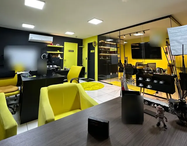 Salão de trabalho com poltronas amarelas e a sala de reunião ao fundo