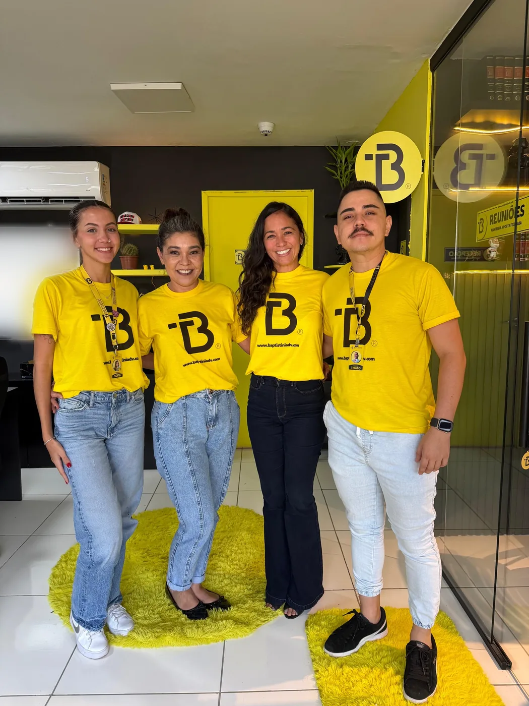 Sofia, duas integrantes da equipe e o Dr. Thiago com as camisetas do escritório na recepção