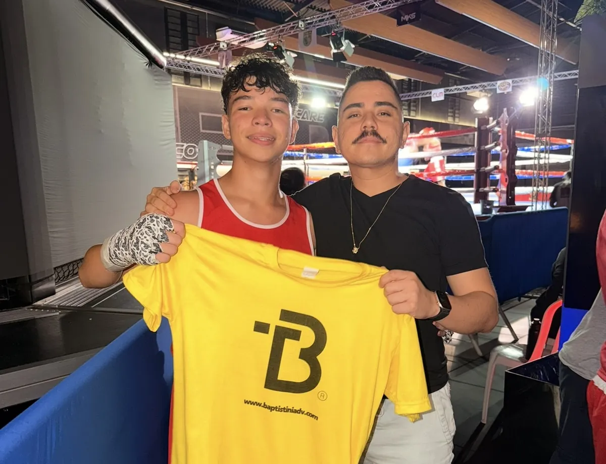 Dr. Thiago e o atleta Thales Francisco segurando a camiseta do escritório ao lado do ringue