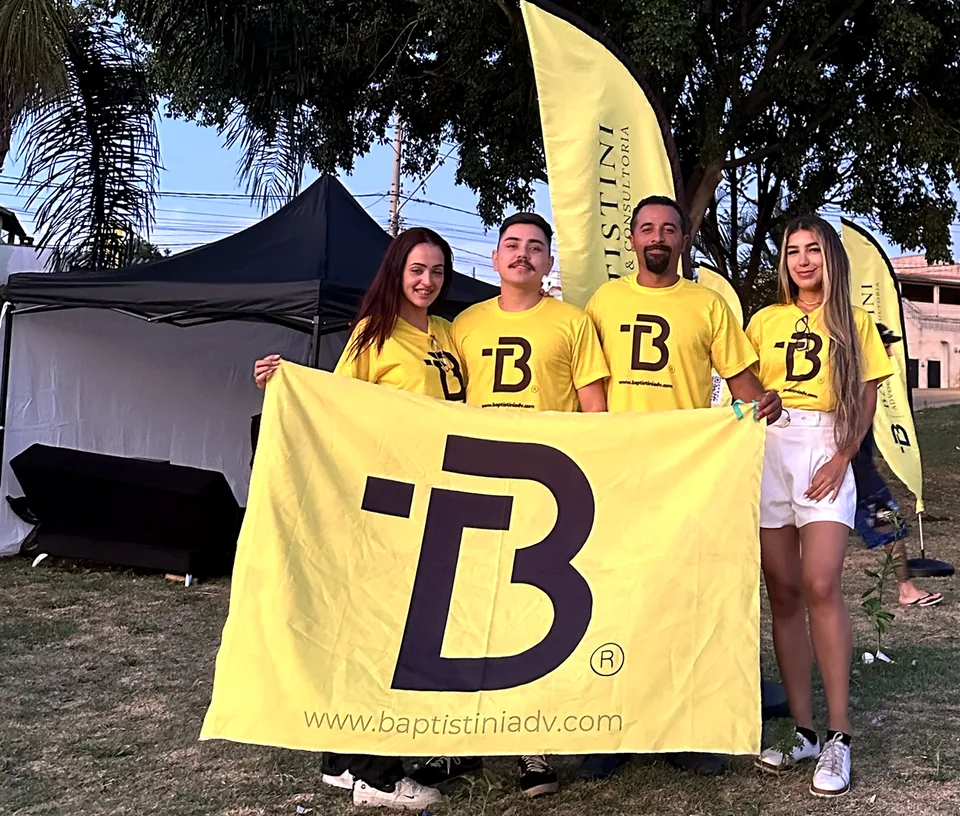 Equipe do escritório com a bandeira do B em frente à tenda jurídica, no Dia das Crianças da comunidade Santo Antônio